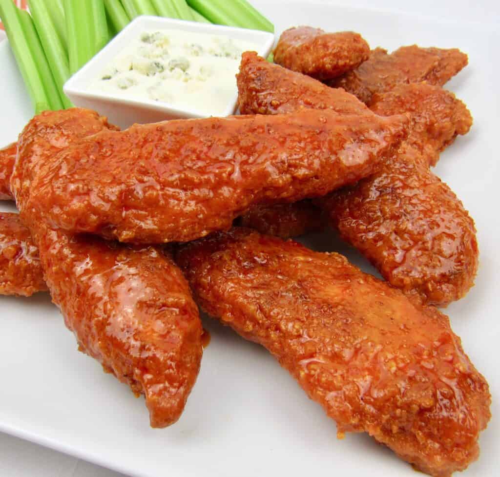 closeup of buffalo tenders on white plate with celery