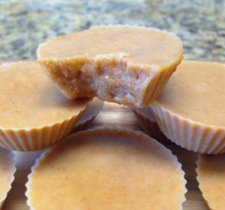 TOASTED COCONUT FAT BOMBS STACKED UP WITH BITE TAKEN OUT OF TOP ONE