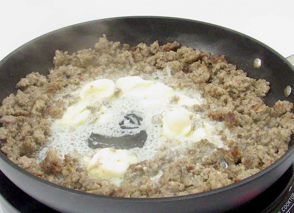 ground sausage in skillet cooked with cheese in the middle