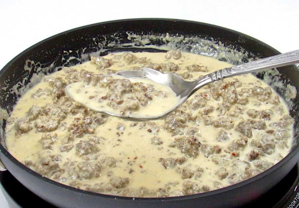 sausage gravy in skillet with spoon holding up some