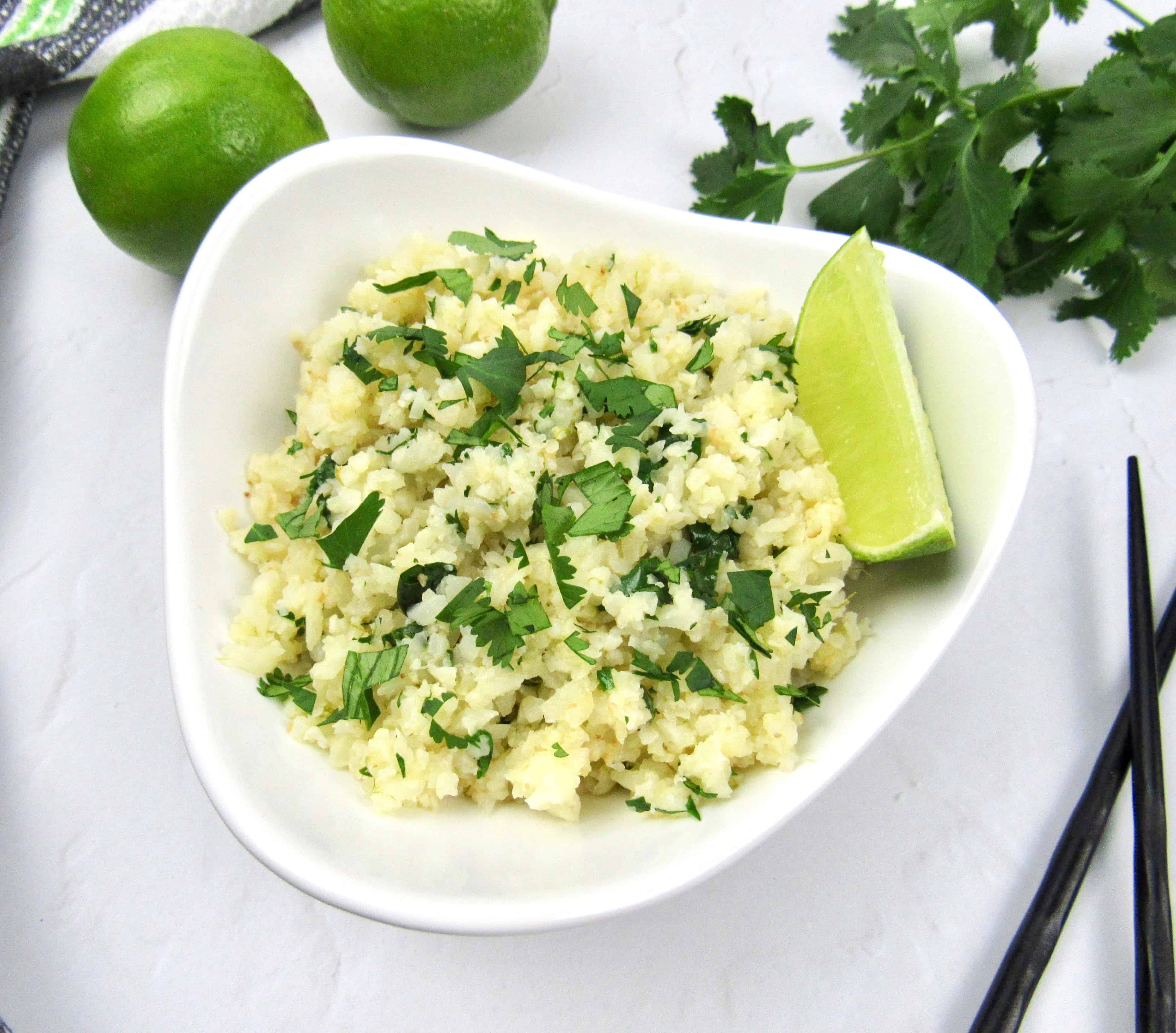Lime cilantro cauliflower rice in white bowl with lime wedge