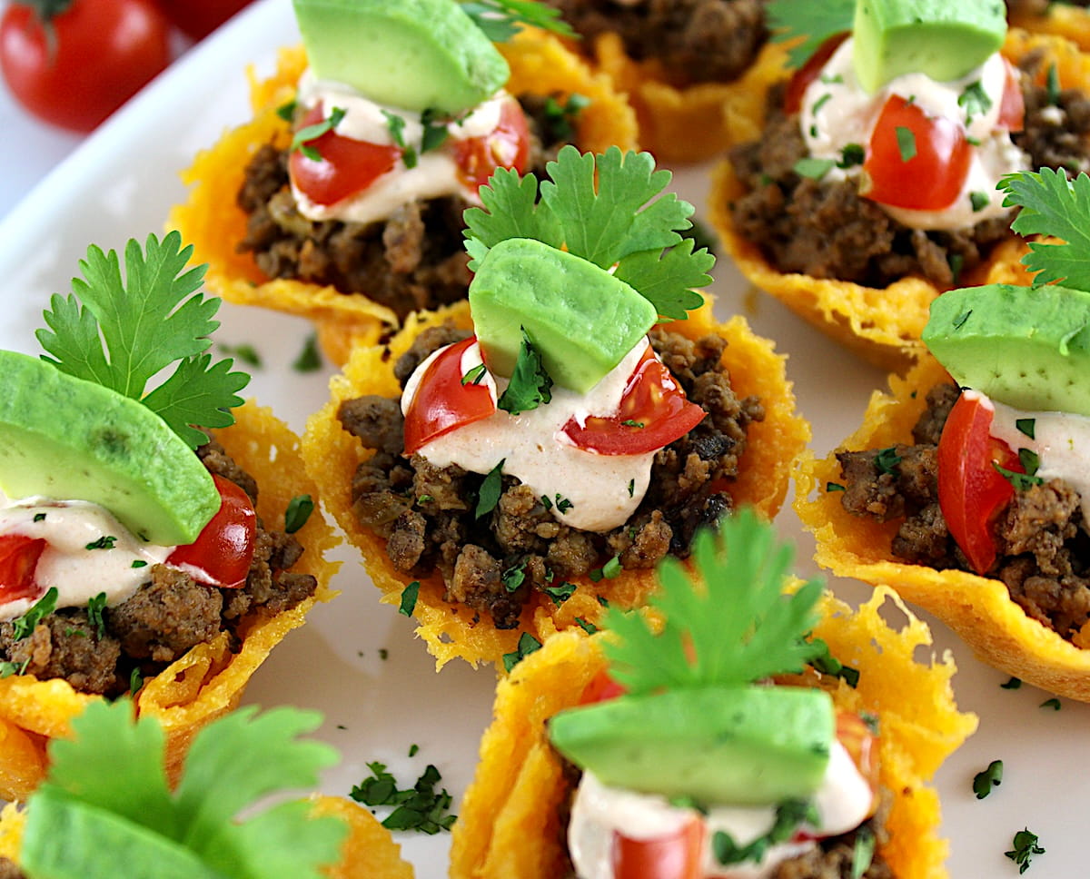 closeup of Mini Taco Bites on white platter with avocado piece on top