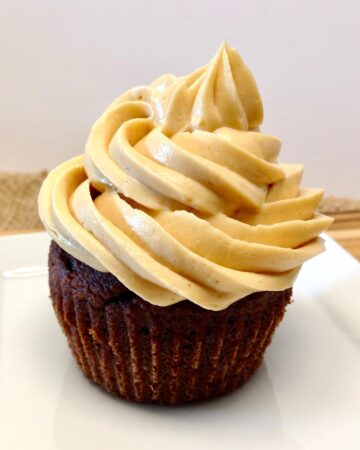 closeup of chocolate cupcake with peanut butter frosting on white plate