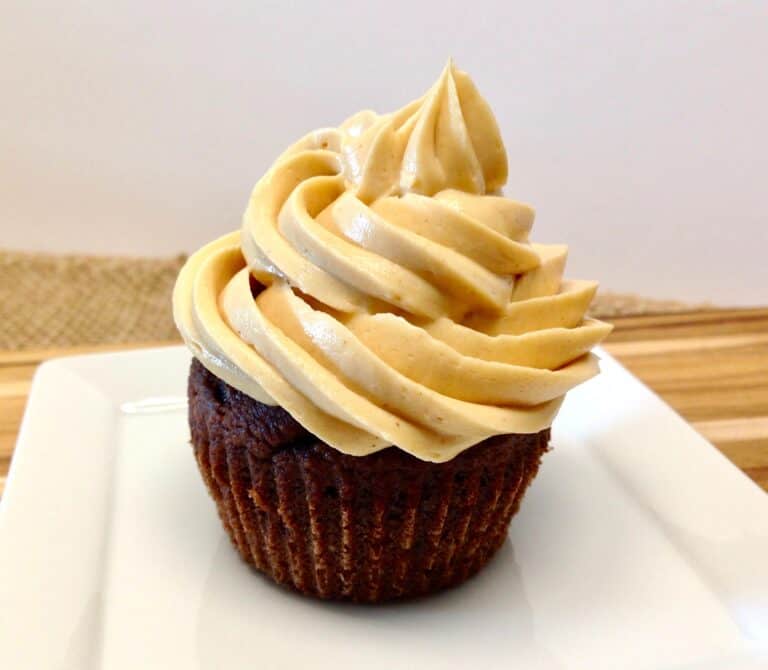 closeup of chocolate cupcake with peanut butter frosting on white plate