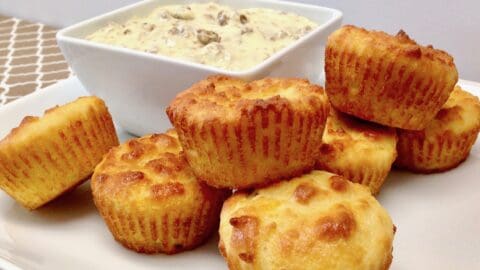 biscuits on white plate with bowl of sausage gravy on the side