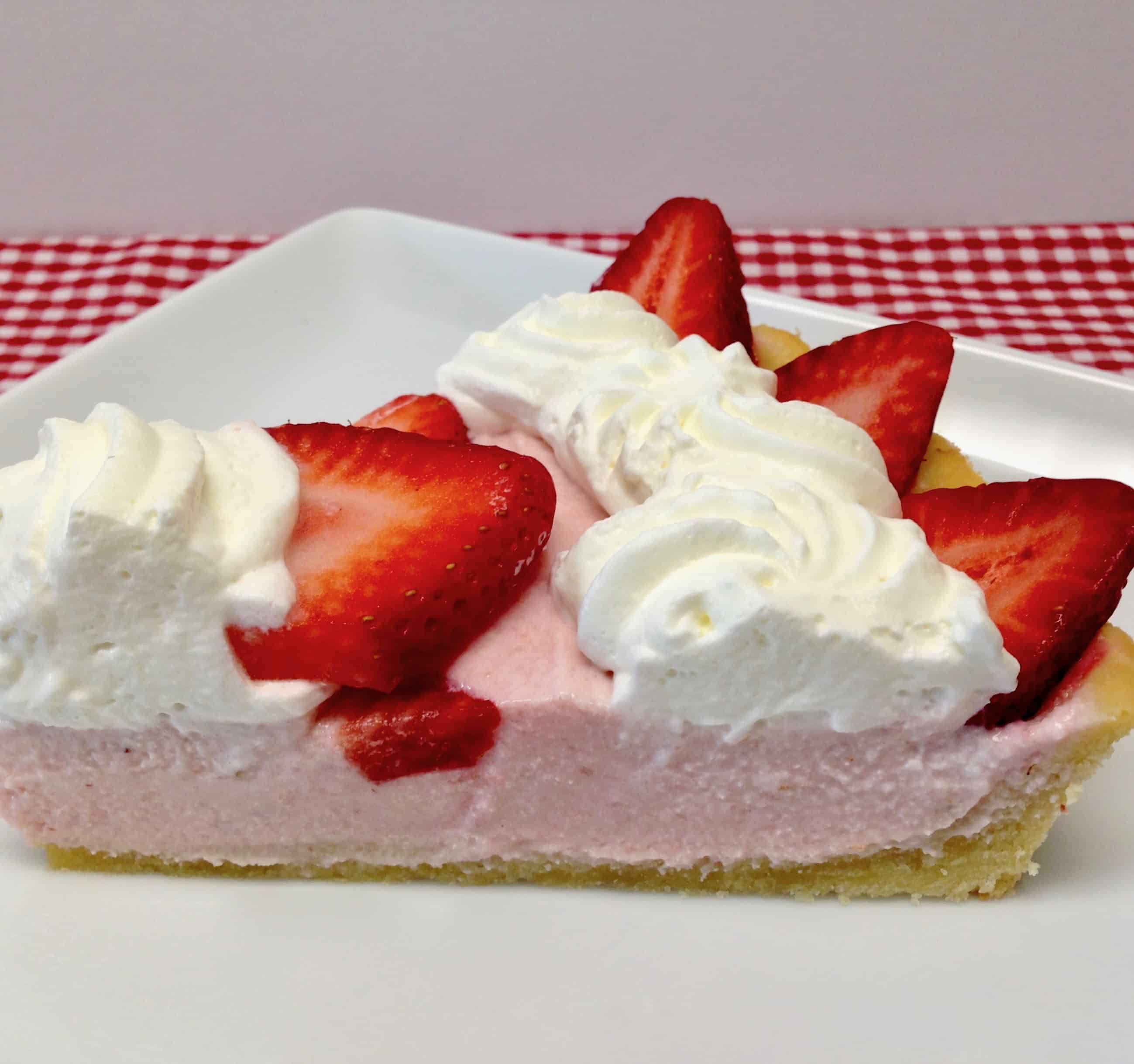 slice of strawberry tart with whip cream and slices of strawberries on top