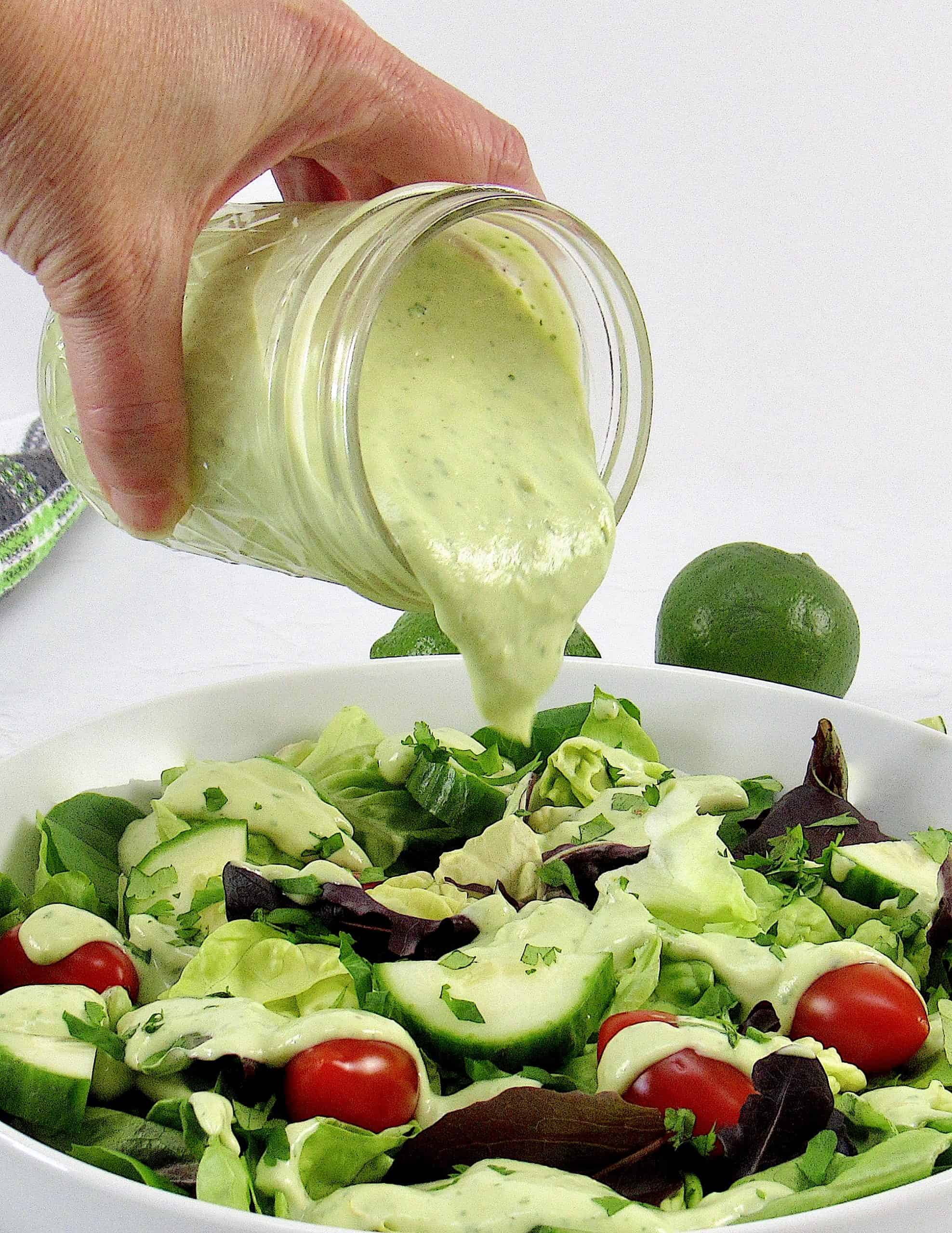 Avocado ranch dressing being poured over salad