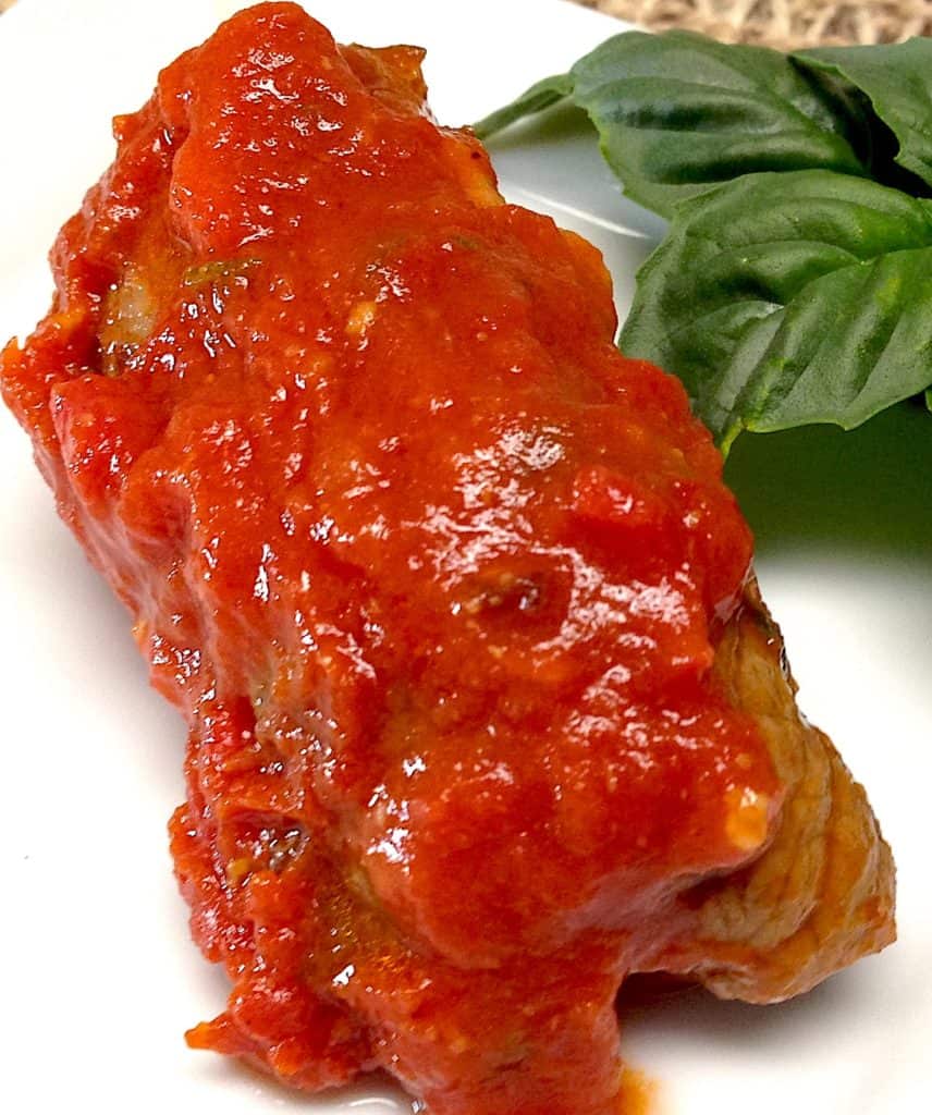 braciole with marinara sauce on top with basil garnish