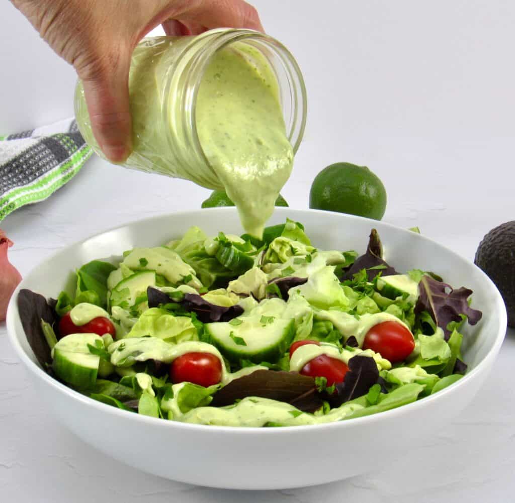 avocado ranch dressing being poured over salad