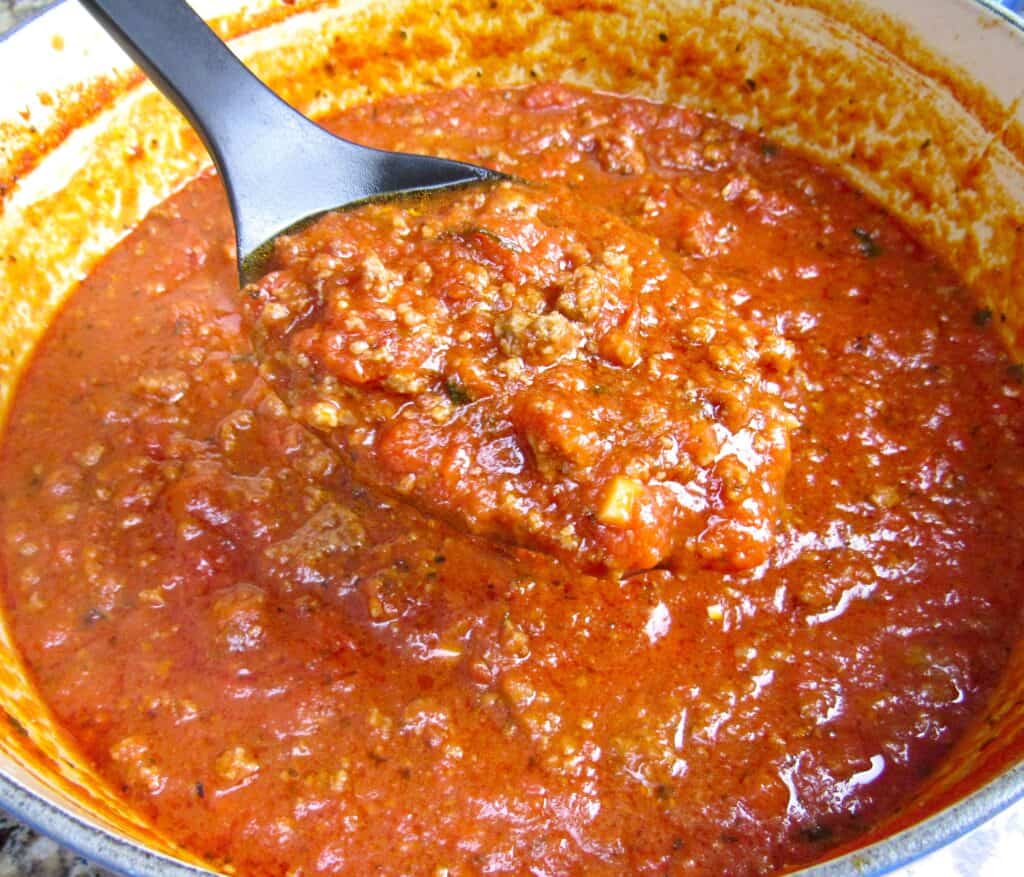 Italian meat sauce in pot with spoon holding some up