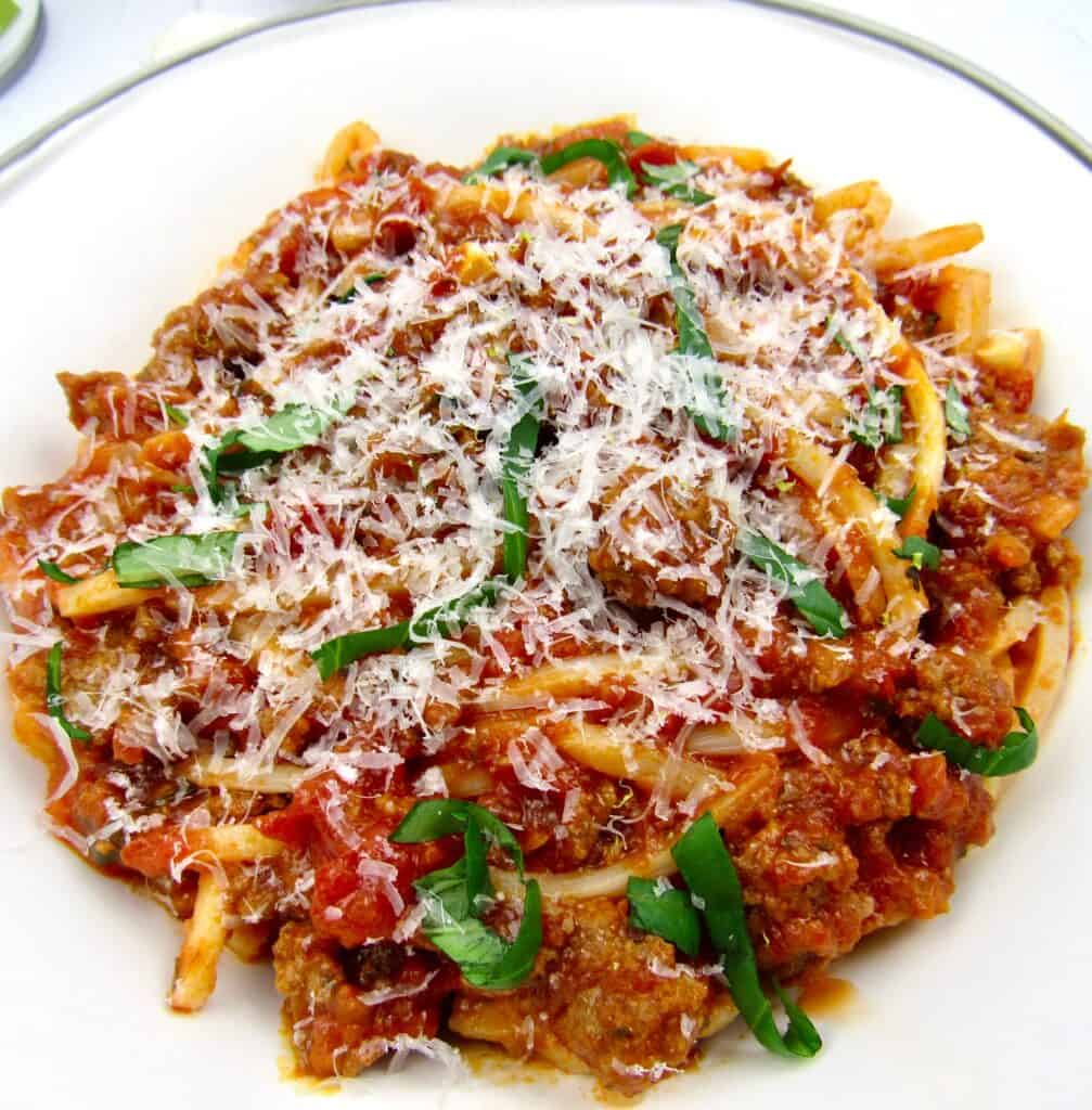 Palmini spaghetti and meat sauce in bowl with grated cheese on top