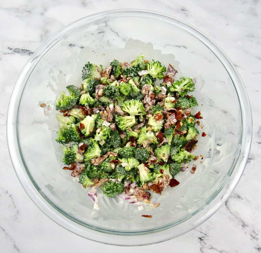 broccoli salad ingredients in glass bowl mixed