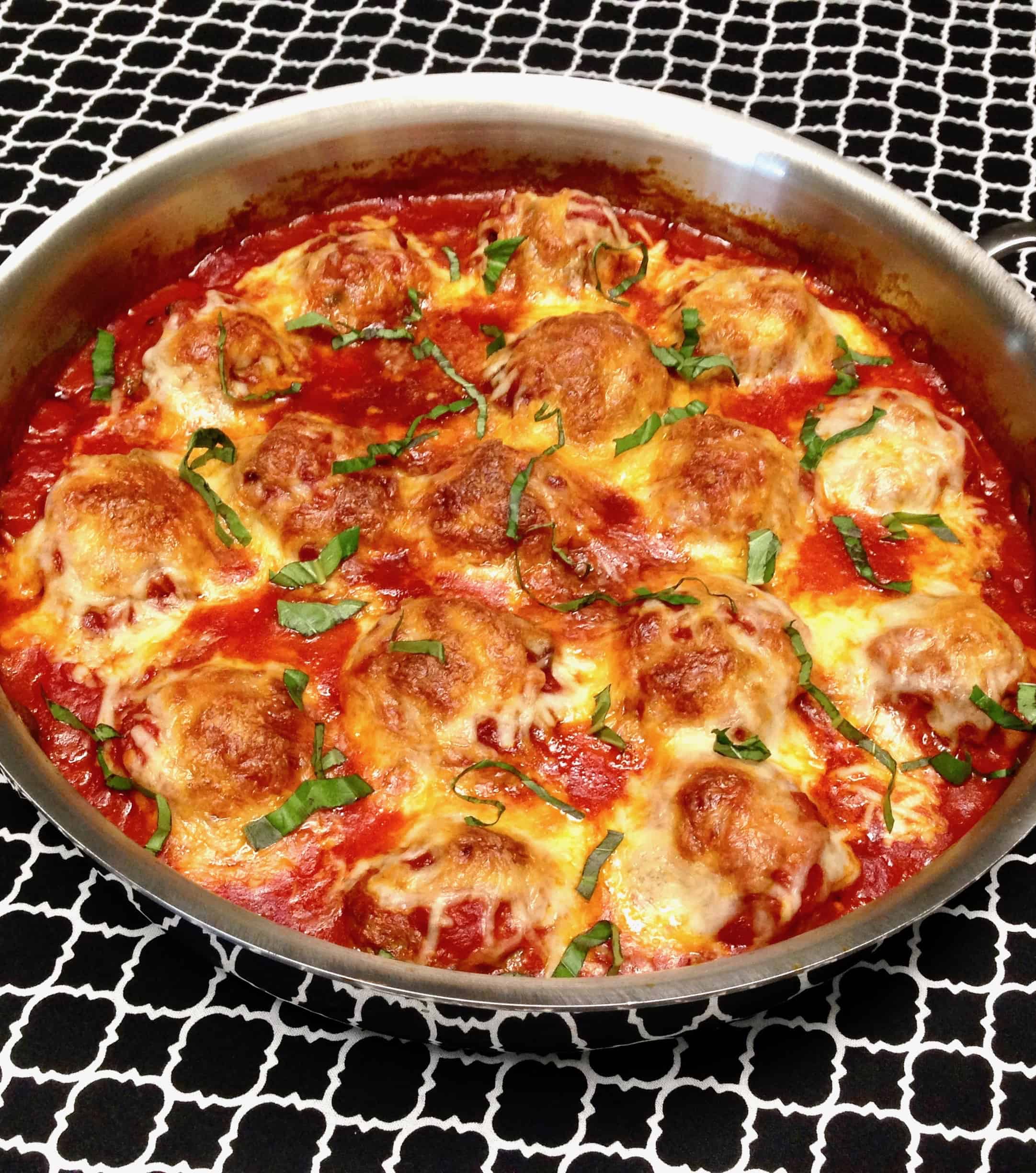 pan of baked meatballs with cheese and basil on top