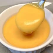 buffalo cheese sauce being spooned out of white bowl
