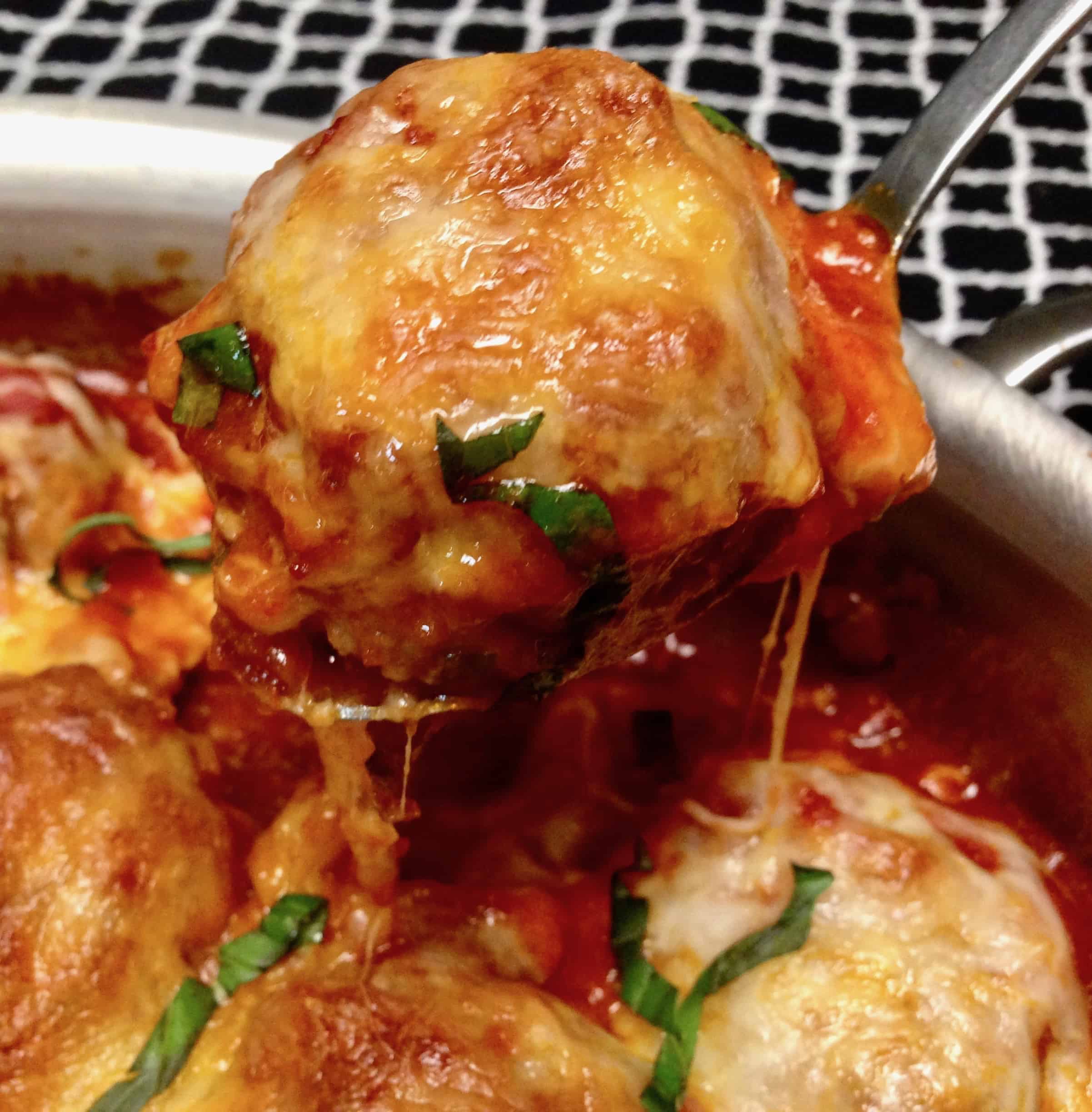 pan of meatballs with closeup of meatball on spoon