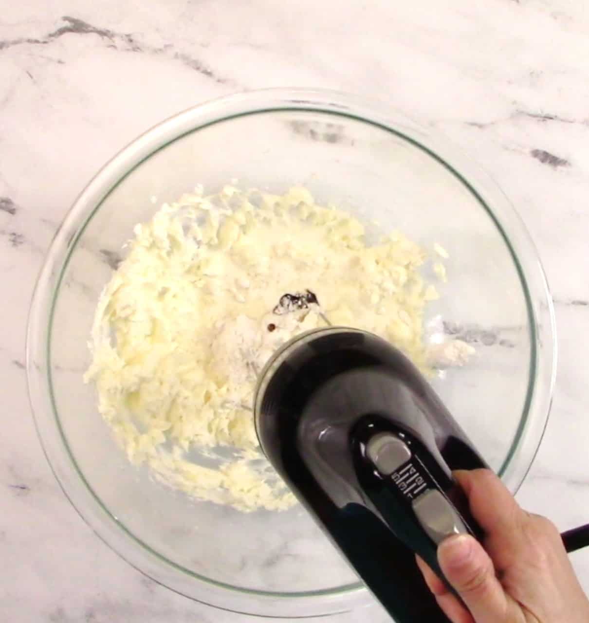 vanilla frosting being mixed with hand mixer