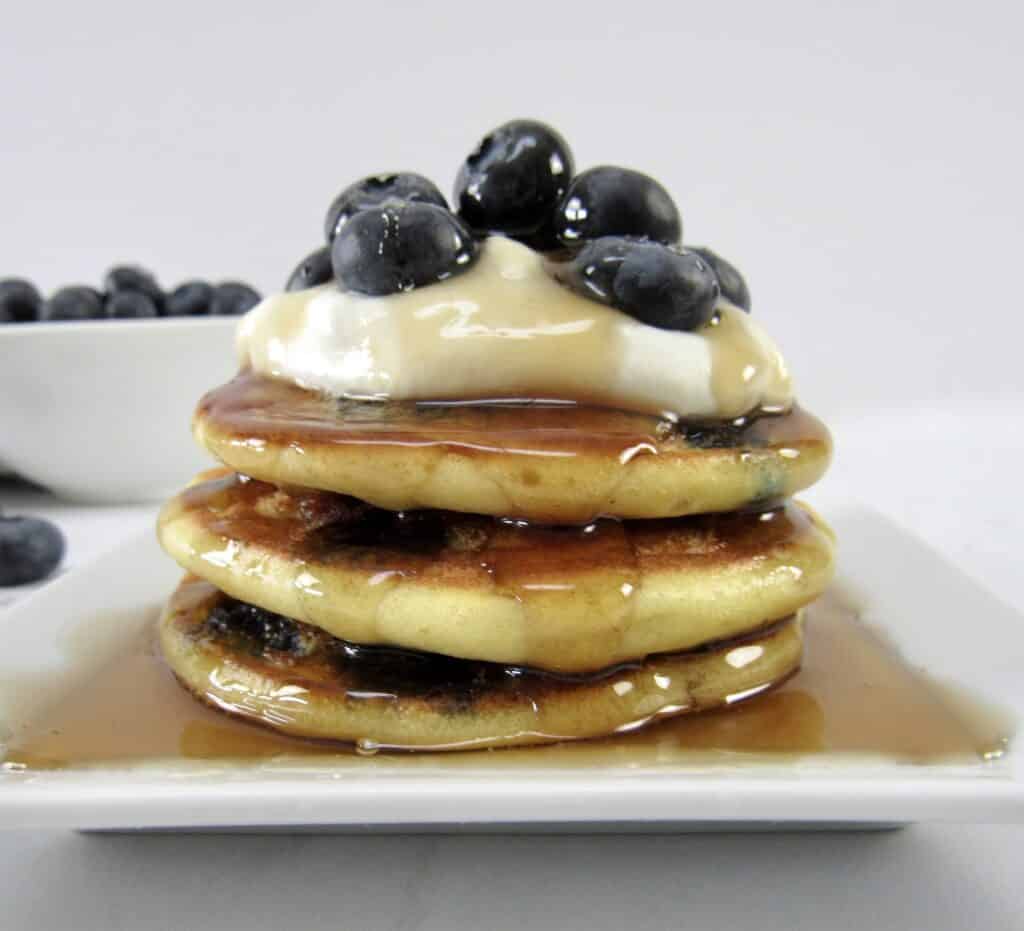 blueberry pancakes with syrup and blueberries on top closeup