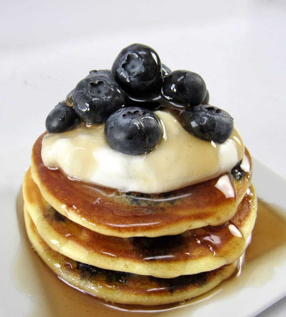 blueberry pancakes with syrup, whip cream and blueberries on top