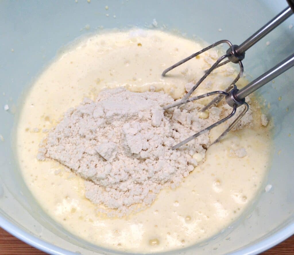 wet and dry ingredients for pancakes being mixed in bowl