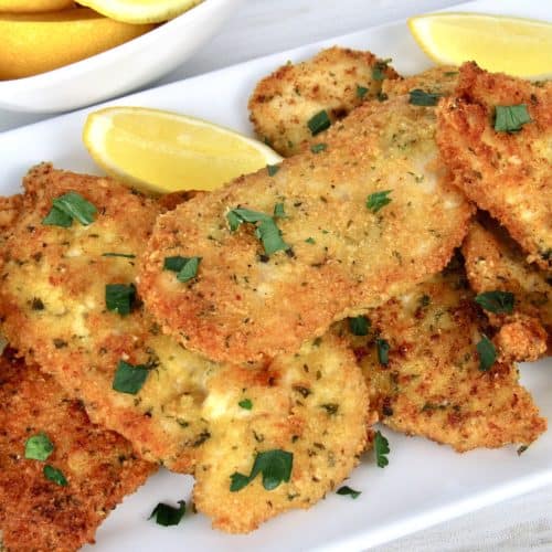 Keto Chicken Milanese on white plate with lemons