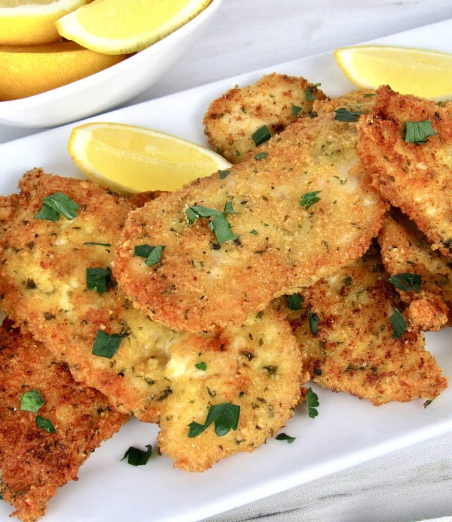 Keto Chicken Milanese on white plate with lemons