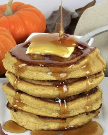 pumpkin pancakes stack with butter and syrup being poured on top