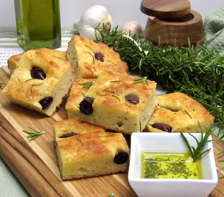 stacked up slices of rosemary and olive focaccia on cutting board