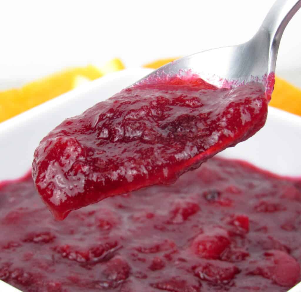 cranberry sauce being spooned out of white bowl