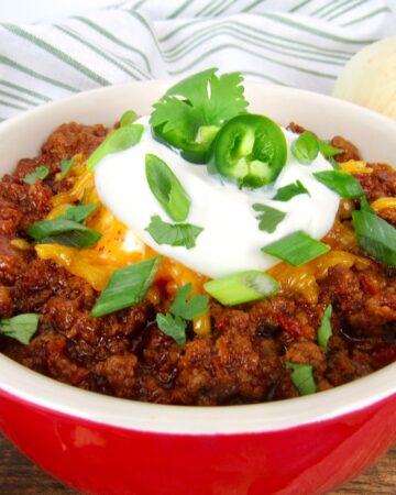 closeup of bowl of chili with sour cream and scallions