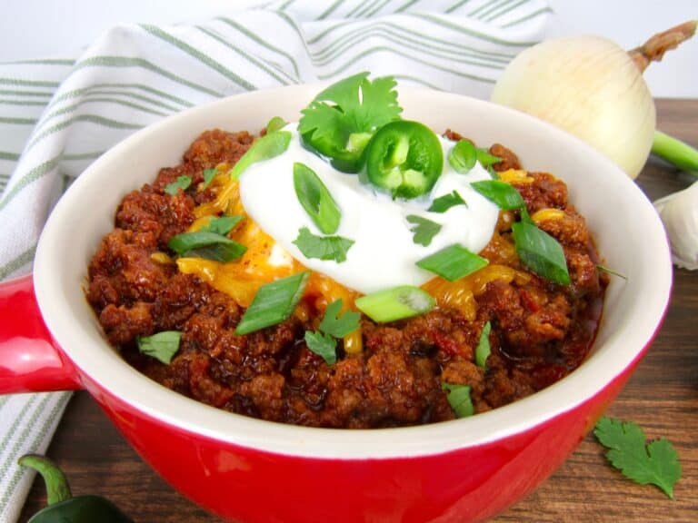 closeup of bowl of chili with sour cream and scallions