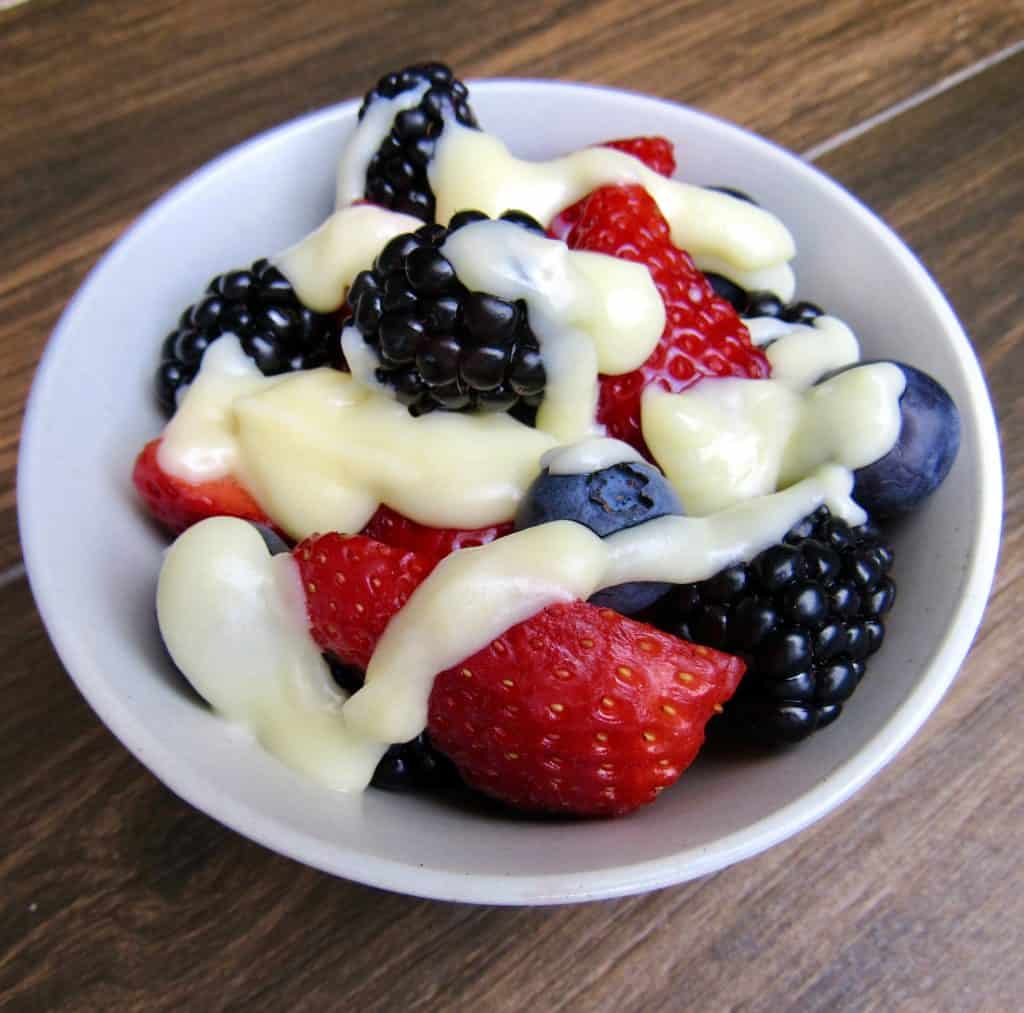bowl of berries with condensed milk drizzled on top