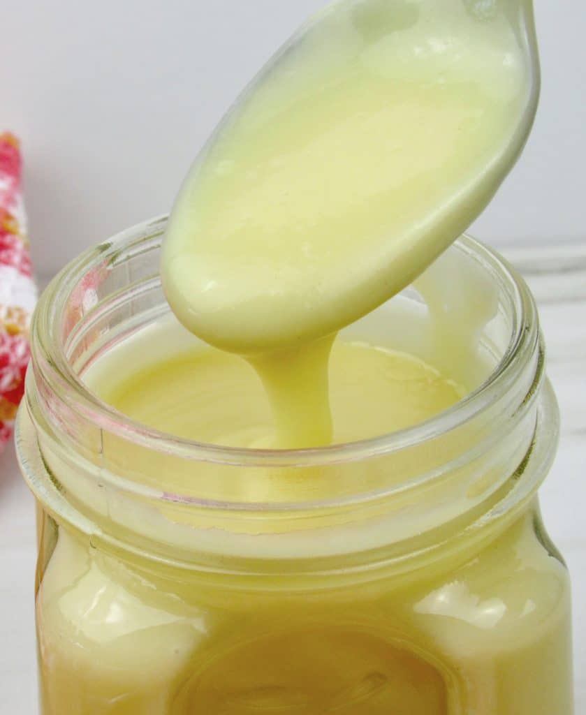 sweetened condensed milk being spooned out of glass jar