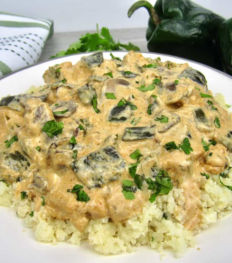 closeup of creamy poblano chicken over cauliflower rice in white plate