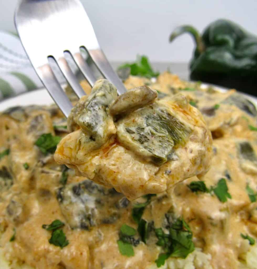 fork holding up creamy poblano chicken over plate