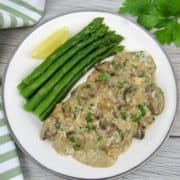 chicken marsala on white plate with asparagus