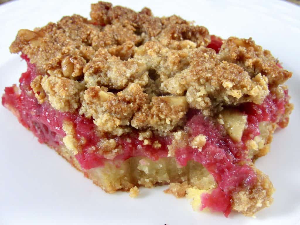 closeup of a cranberry walnut crumble bar on white plate