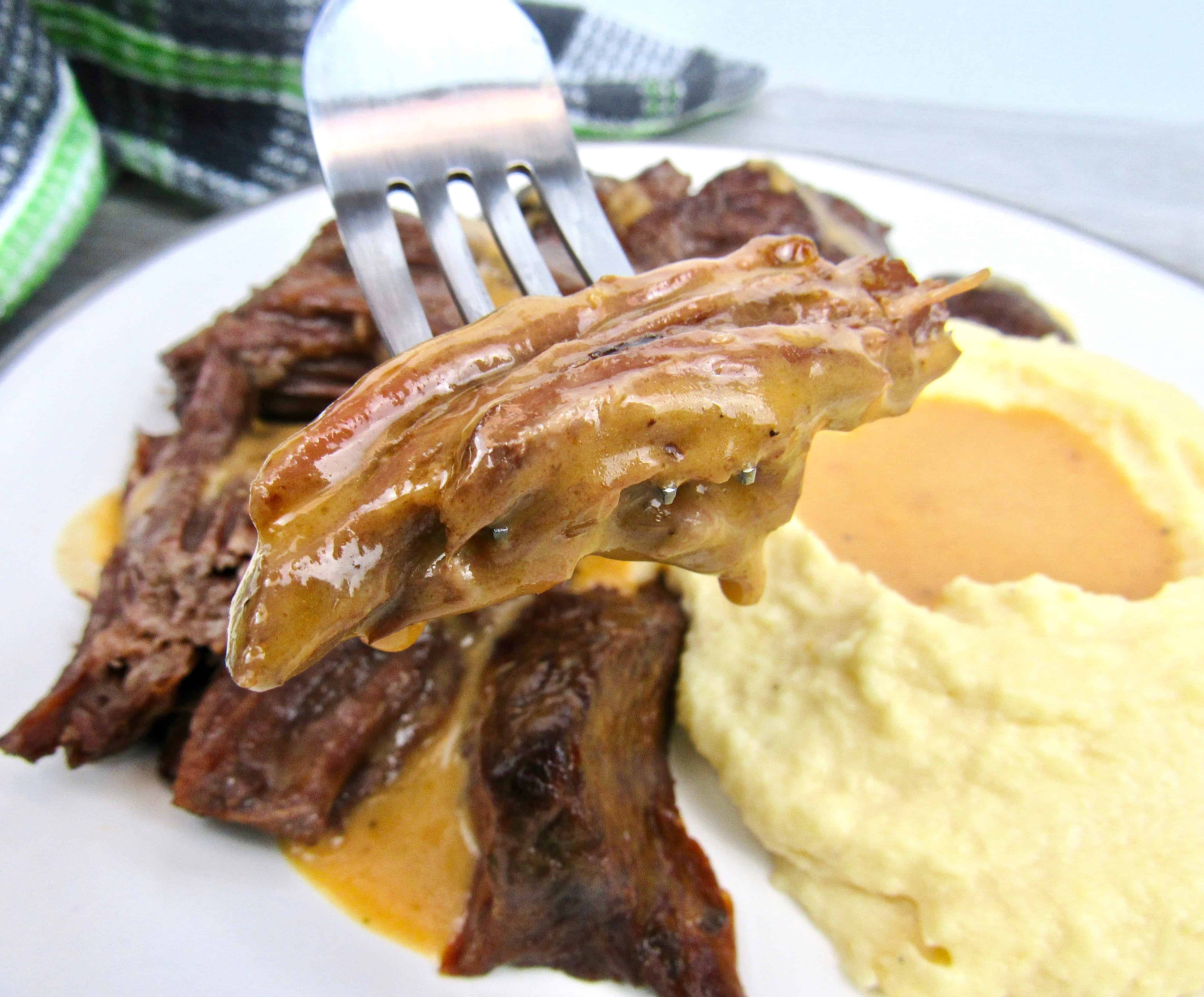 closeup of pot roast on fork with gravy dripping