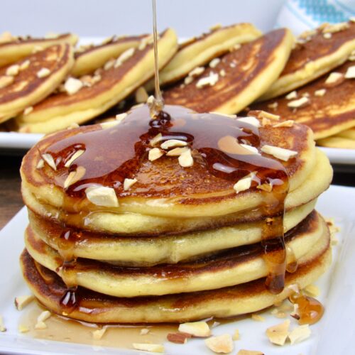 stack of pancakes with syrup being poured over the top