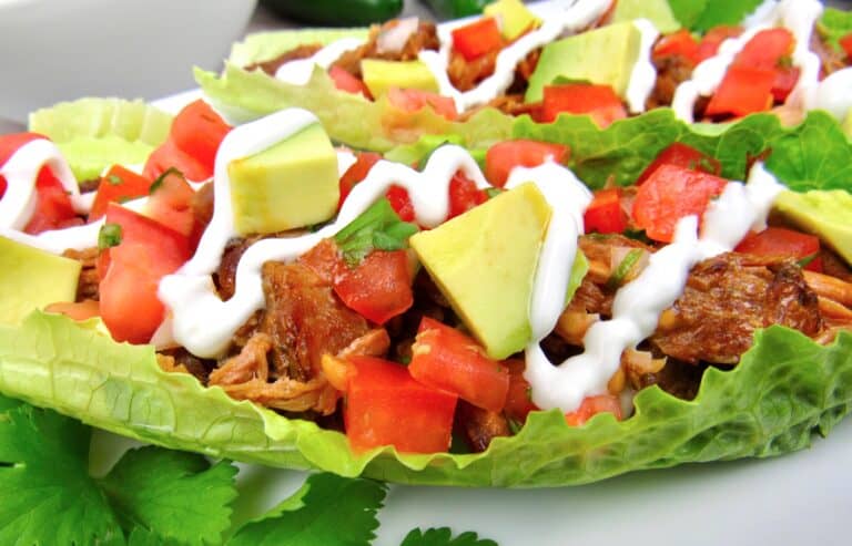 closeup of pork carnitas in lettuce wrapped with sour cream drizzle on top
