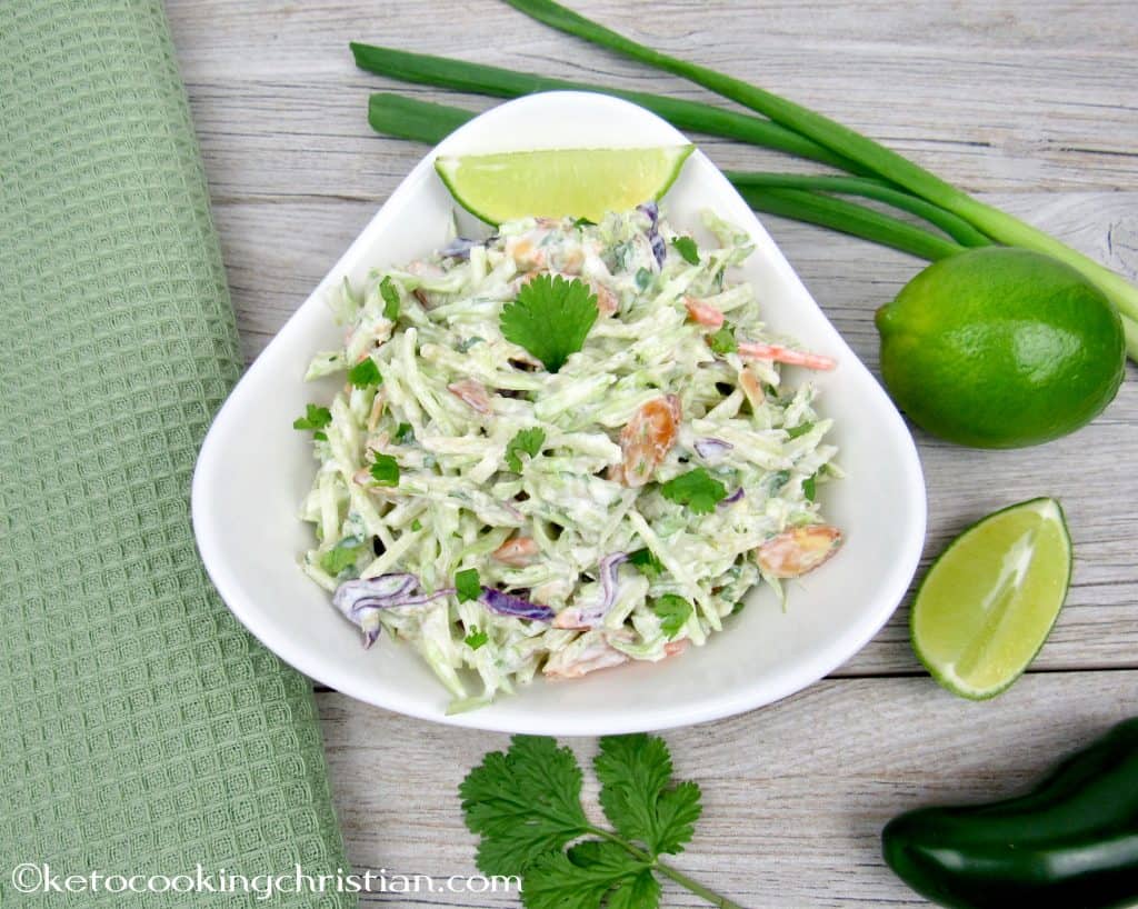 bowl of lime cilantro slaw with a slice of lime at the top of the bowl