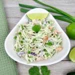 bowl of lime cilantro slaw with a slice of lime at the top of the bowl