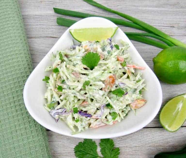 bowl of lime cilantro slaw with a slice of lime at the top of the bowl