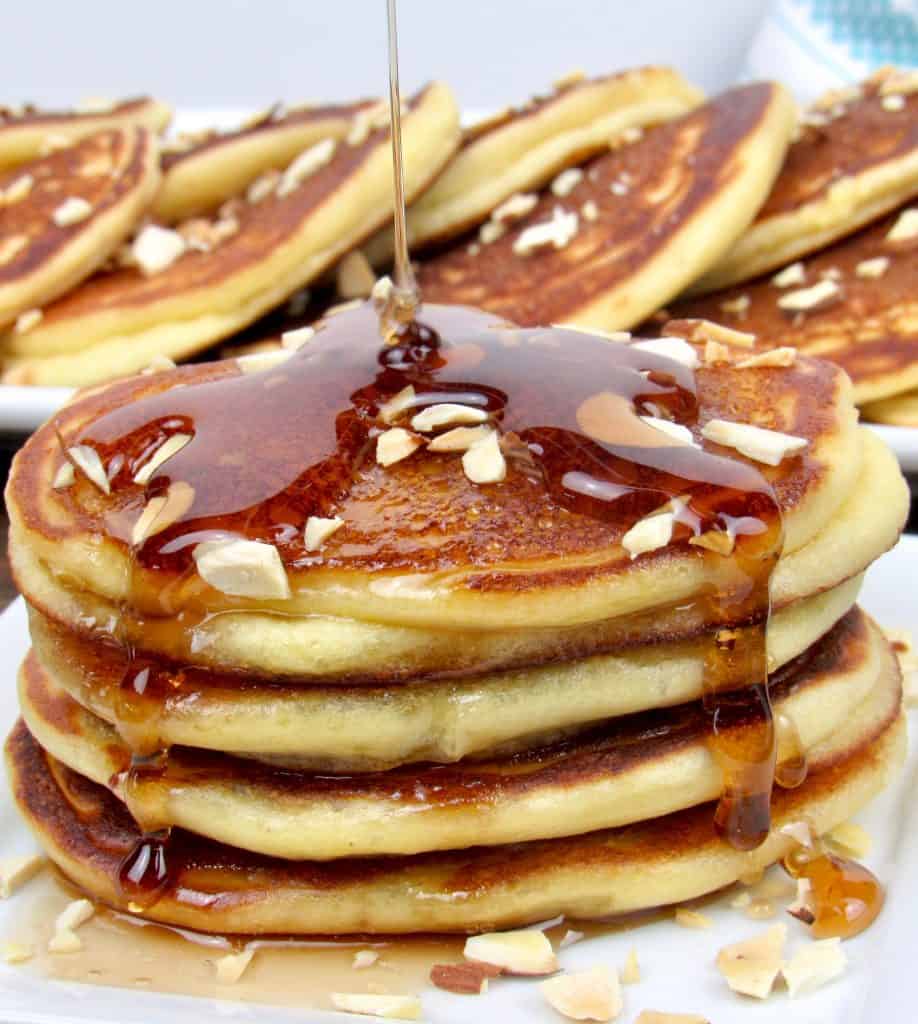 stack of pancakes with syrup being poured over the top