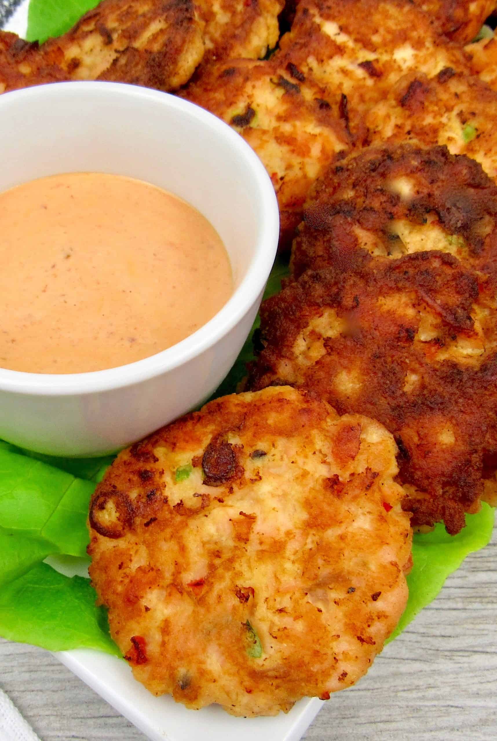 Keto Bang Bang Salmon Cakes on plate with lettuce and dipping sauce on side