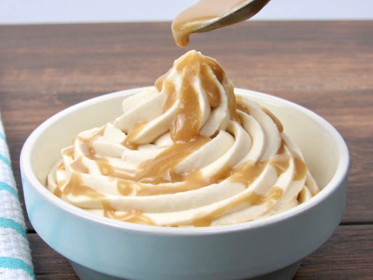 cheesecake mousse swirled into a cup with spoon dripping salted caramel over the top