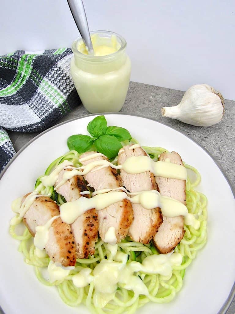 zucchini noodles with sliced chicken and alfredo sauce on top