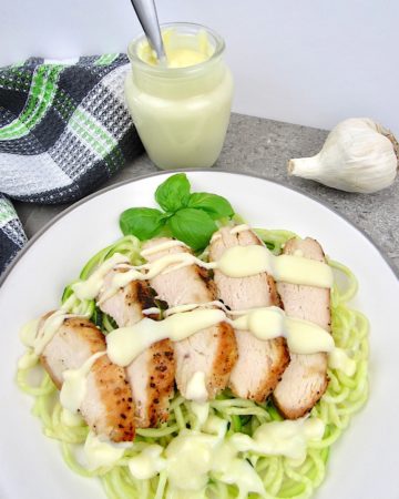 zucchini noodles with sliced chicken and alfredo sauce on top