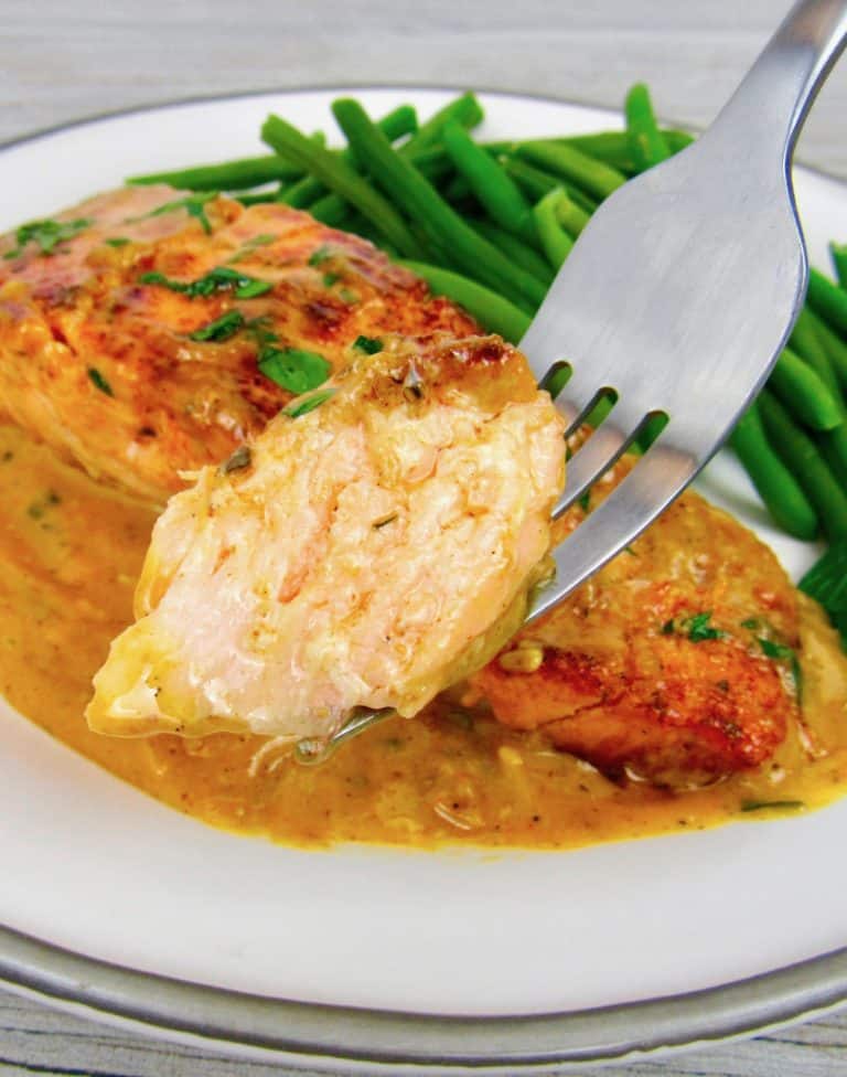 fork holding up piece of salmon alfredo