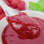 closeup of raspberry sauce in spoon over a bowl
