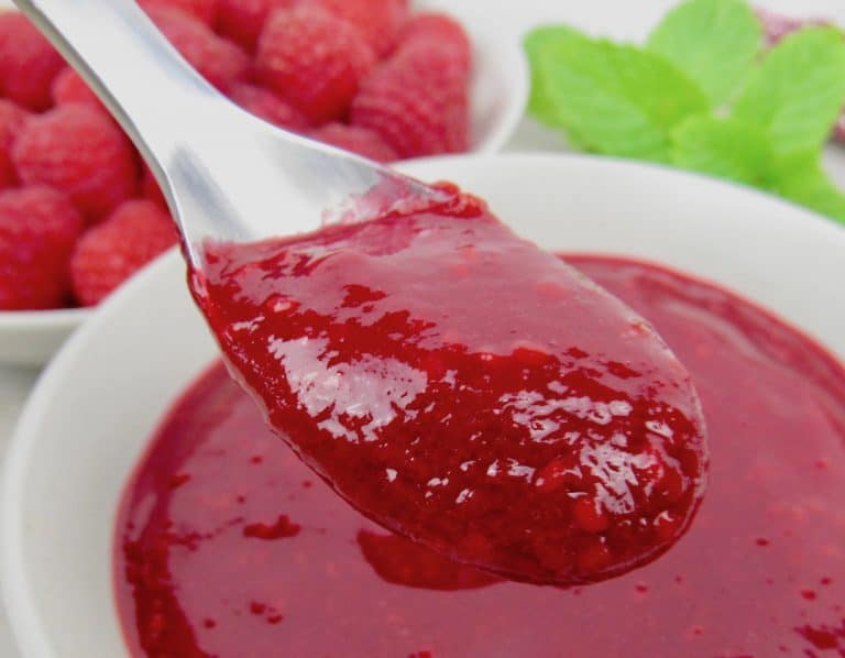 closeup of raspberry sauce in spoon over a bowl